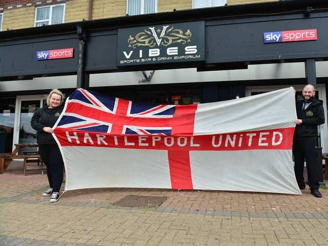 Leeroy Newsome, the general manager at Vibes sports bar, in Navigation Point, with bar manager Georgina Cooper with a giant Hartlepool United and England flag. Picture by FRANK REID.