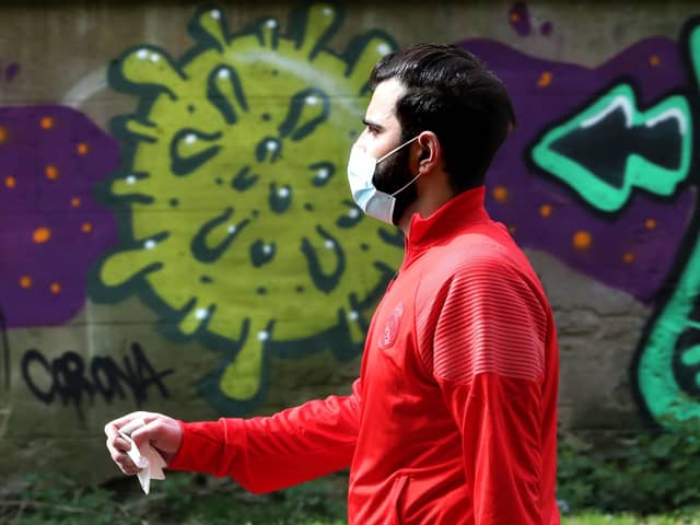 A man wearing a mask walks past coronavirus related graffiti as the UK continues in lockdown to help curb the spread of the coronavirus. Andrew Milligan/PA Wire