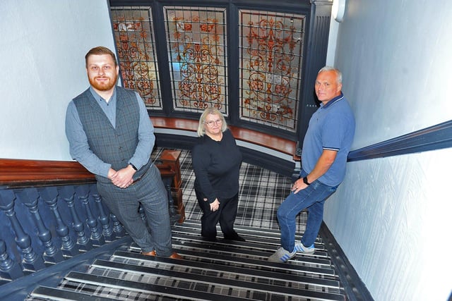 Nathan Longthorne, general manager, Irene Southern, head housekeeper, and Brian Keane, CEO of Otway Capital, pose for a photo on the staircase at the Grand Hotel in 2023.