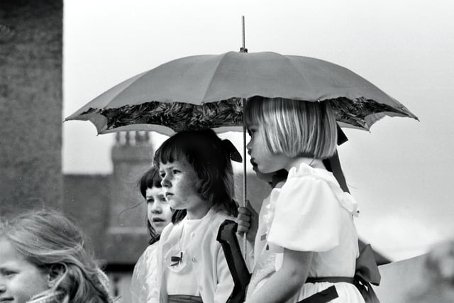 Little girls with an umbrella hope the rain won't spoil the Lanimar Day parade taking place in Lanark in June 1974.