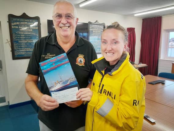 Author Mick Coverdale presents his cheque to RNLI trainee crew member Danielle Austin.
