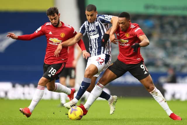 Bruno Fernandes (L) and Anthony Martial (R) of Manchester United battle for possession with Lee Peltier of West Bromwich Albion.