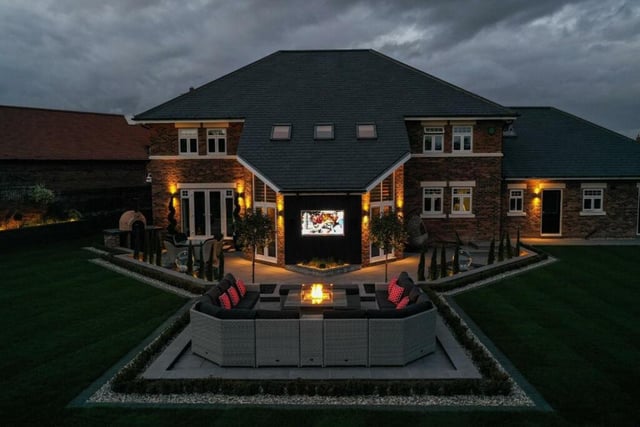 This home has an excellent outdoor entertaining space featuring stylish seating areas, a pizza oven and a UHD TV screen.