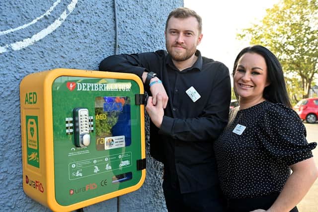 Sarah Lowther, general manager, and Matt Grocott, stand next to the defibrillator that was installed by DS43 Community Defibrillators.
