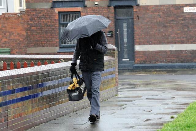 A walker takes shelter during Monday's downpours in Hartlepool.