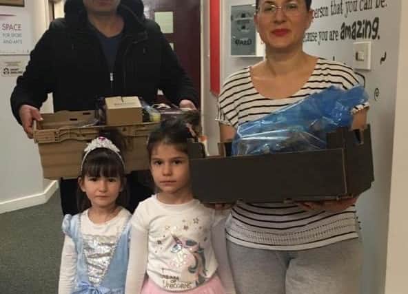 The Ikonomi family collect their food hamper from West View Primary School. Daughters Sloudia and Mirsia are dressed in tutu for the occasion