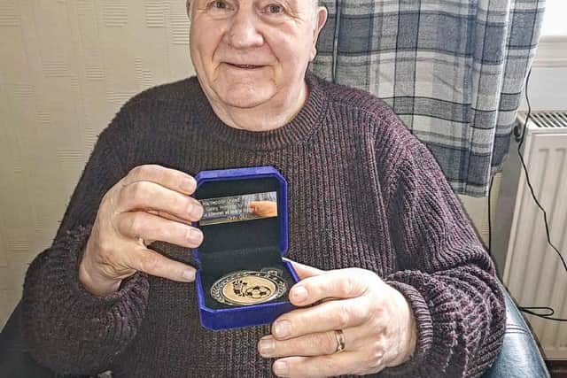 John Gill, 83, with his promotion medal.