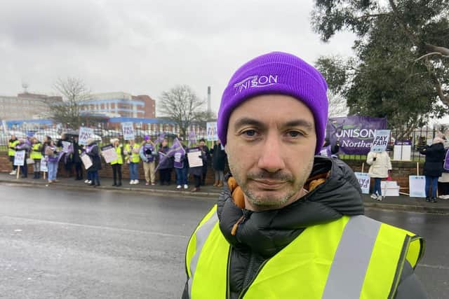 David Newey, UNISON area organiser, stands outside the University Hospital of Hartlepool alongside healthcare assistants who are on strike over a dispute in pay.
