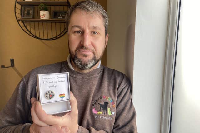 Darren Bates (44) owner of Roxy's Rainbow Pet Cremation holding a "pin badge". by FRANK REID