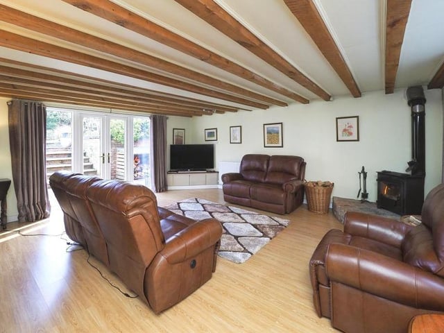 The tour begins in this lovely lounge, which is light, spacious and full of character. In the corner sits a feature free-standing log burner on an elevated hearth. The floor is laminated, and French doors open out into the garden.