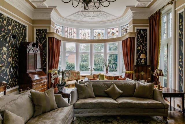 The drawing room is a large entertainment space featuring a Tudor style ceiling and a large bay window topped with stained glass pictures of famous poets and authors.