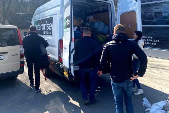 Refugees help to unload the van.