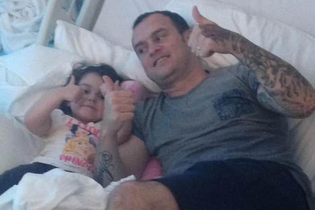 Courageous Lyla still manages a thumbs-up from her hospital bed, with dad Paul by her side.