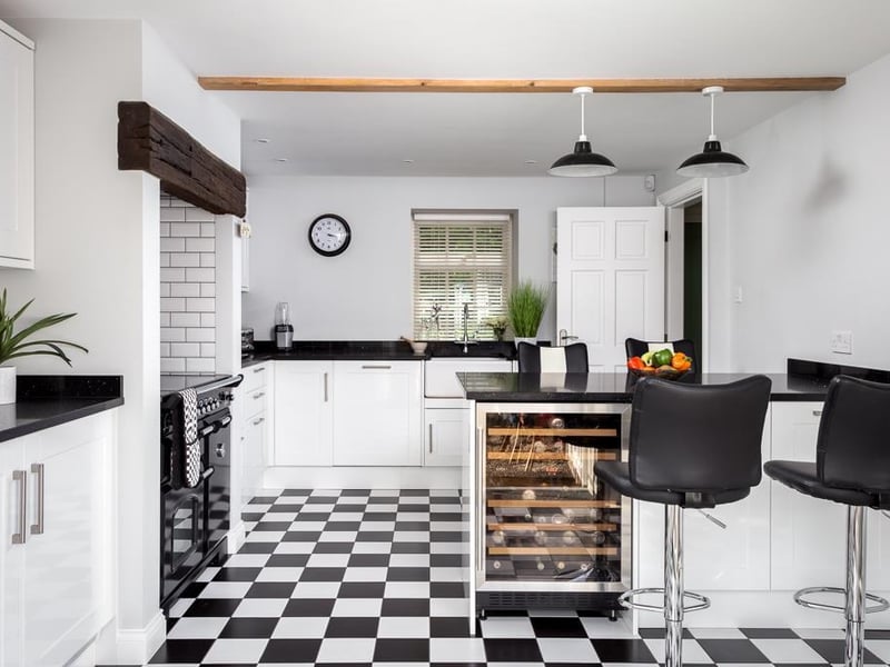 This stylish kitchen diner features high quality shaker style, white gloss fitted units with black quartz work surfaces and fitted appliances, plus a central island with seating.
