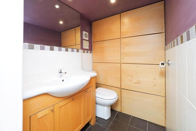 Also on the ground floor is this cloakroom, which is fitted with a low-level WC and wash hand basin with vanity unit. The floor and part of the walls are tiled, while spotlights to the ceiling, an extractor fan and built-in storage add to the usefulness of this room.