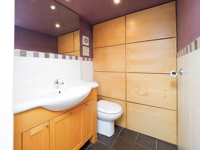 Also on the ground floor is this cloakroom, which is fitted with a low-level WC and wash hand basin with vanity unit. The floor and part of the walls are tiled, while spotlights to the ceiling, an extractor fan and built-in storage add to the usefulness of this room.
