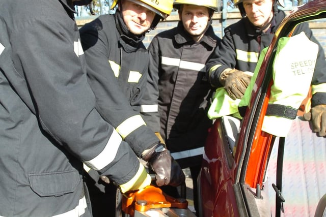 Students David Dawson and Chris Serle, force open the driver door of a crashed car alongside firefighter Doug Stephenson and watch manager, Ian Brown, in 2010.