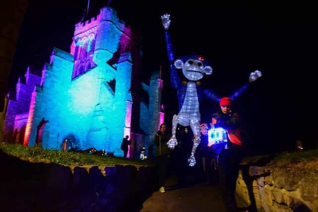 Flashbak to last year's opening lantern parade with large monkey puppet past an illuminated St Hilda's church.