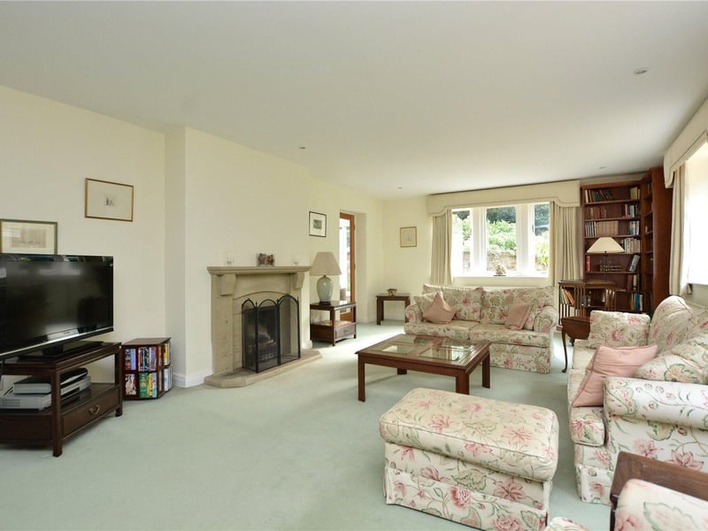 The generously sized living room is bathed in light from the large windows and boasts an attractive feature stone fireplace at its heart.