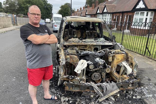 Paul Brackstone alongside of his burnt out Range Rover in Brinkburn Road. Picture by FRANK REID
