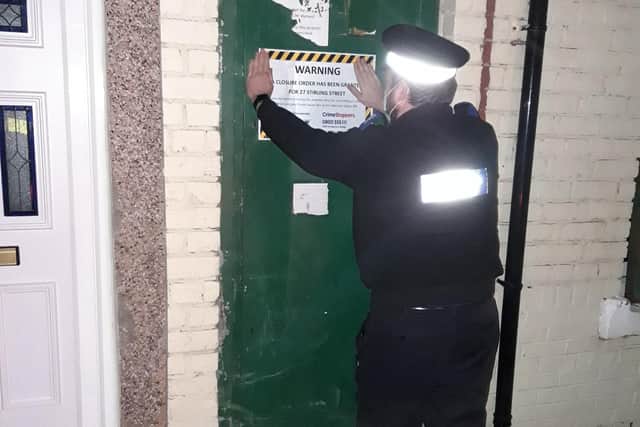 An officer fixes the closure order notice to the front of one of the houses in Stirling Street.