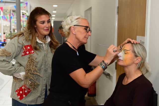 Michelle of Moon Willow Face Painting puts the finishing touches to the Cowardly Lion, Catherine Wilthew, watched by Scarecrow Grace Kidson for The Wizard of Oz production.