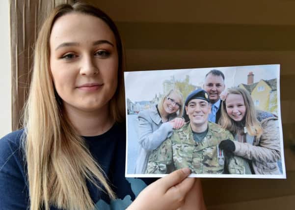 Shauna-Leigh Winspear holding a photograph of her with her dad Craig and partner Hayley and Craigs dad Paul