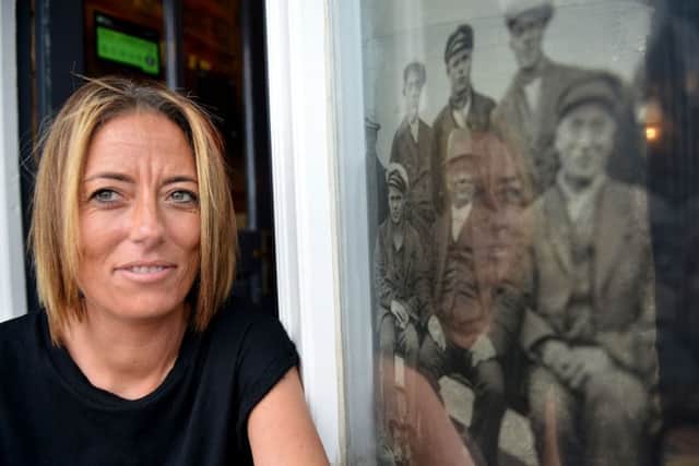 Lorna Hogan in front of the pub's window depicting the nine rescued sailors.