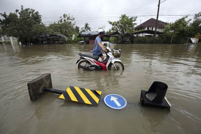 Thai people push a motorcycle through floodwater from Tropical Storm Pabuk, Friday, Jan. 4, 2019, in Pak Phanang, in the southern province of Nakhon Si Thammarat, southern Thailand. Rain, winds and surging seawater are striking southern Thailand as a strengthening tropical storm nears coastal villages and popular tourist resorts. (AP Photo/Thanis Sudto)