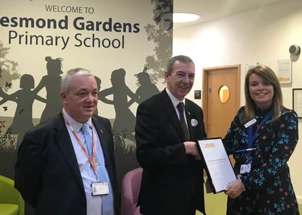 Mike Hill presents the award to Jesmond Gardens parent support advisor Carly Lupton with chairman of governors Peter Ingham looking on.