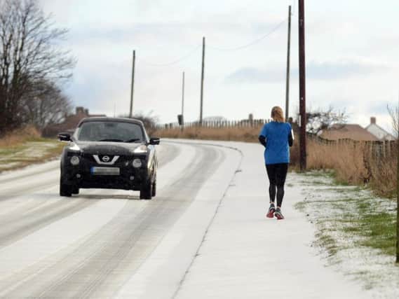 A jogger passes a motorist on a snowy road.