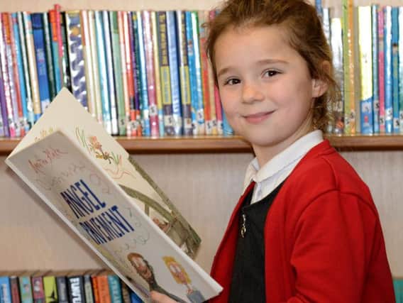 St Helen's primary school pupil Mia Pearce, enjoying her reading, this was subject that was praised in the report.