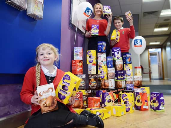Tracey McDermott (Member representative from Nationwide Building Society) handing over Easter eggs for the Foodbank to Holy Trinity CofE Primary School pupils Scarlette Mason (9) and Benjamin Cooper (9).