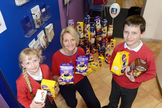 Tracey McDermott (Member representative from Nationwide Building Society) handing over Easter eggs for the Foodbank to Holy Trinity CofE Primary School pupils Scarlette Mason (9) and Benjamin Cooper (9).