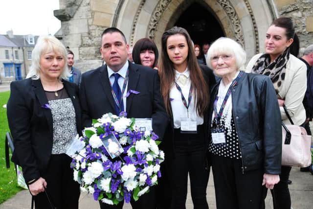 Maria and Trevor Burden (left) with family members hold a wreath in memory of their son Jason at a previous service