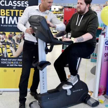 Chris Richardson from Xercise4Less times Boots customer adviser Jason Balderson as he rides the exercise bike in aid of Zoe's Place baby hospice.