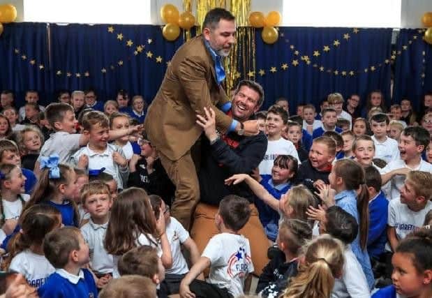 Britain's Got Talent judge David Walliams pictured with headteacher Dave McPartlin and the children at Flakefleet Primary School. Picture: PA.
