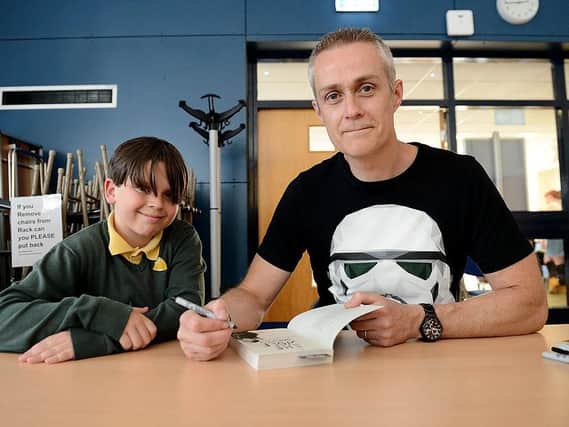 Bestselling children's author Dan Smith signs one of his books for Fens Primary School pupil Theo Ward.  Picture by FRANK REID