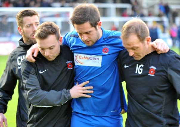 Matty Dolan is helped from the pitch after sustaining an injury during the warmup before the game against Oxford United. Picture by FRANK REID