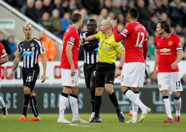Referee Anthony Taylor separates Manchester United's Jonny Evans and Newcastle United's Papiss Demba Cisse
