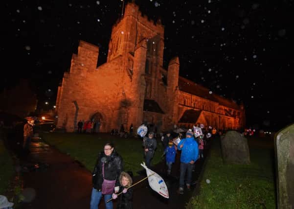 The Wintertide lantern parade passes through the grounds of St. Hilda's Church