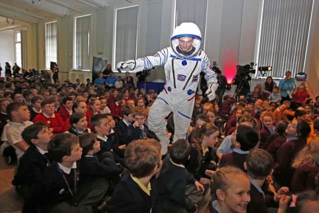 A man in a space suit with children at  Liverpool's World Museum as they take part in Cosmic Classroom event.