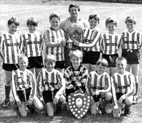 Cotsford Junior School football team with their trophies and sponsor Ken Hall of Biceps Gym, front from left:  Darren Atkinson, Colin Bell, Davie Rowe, James Huntley, Carl Chisholm;  back row: Owen Penfold, Michael Kirby, John Stobbs, Stephen Temple, Wesley Hepburn, Andrew McIntosh. Date unknown.