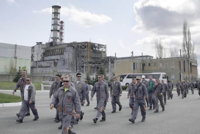 Construction workers pass by the exploded reactor at the Chernobyl nuclear power plant in Chernobyl, Ukraine.