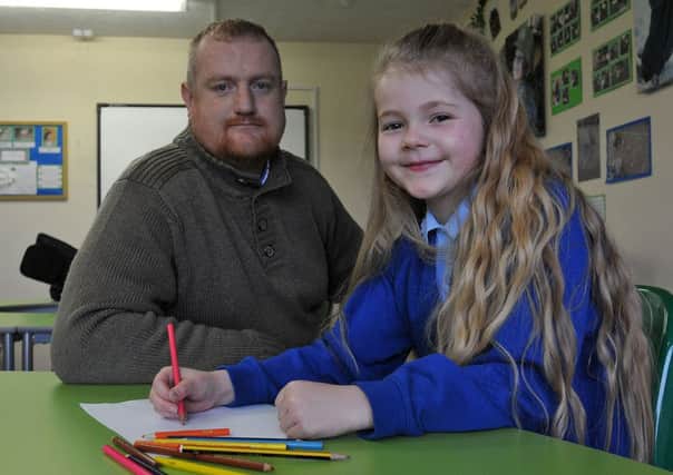 Jonathan McGann from North East Kidney Patients Association looks on as Hart Primary School pupil Annabelle Myers designs her poster.