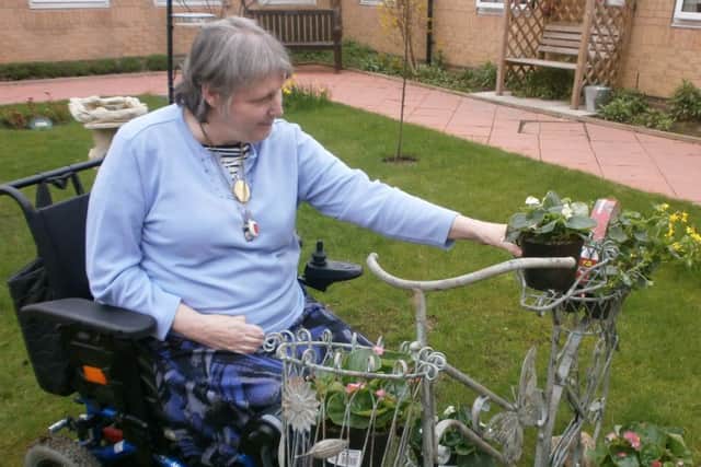 Resident Ann Parker planting flowers in an ornamental bike in Field View care home courtyard.