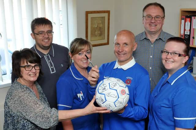 Reunion evening organisers (rear left to right) Andy Wilson and Phil Dunn look on as (former Hartlepool United player Brian Honour signs a ball for Hartlepool and District Hospice staff (left to right) Janice Forbes, Kay Connor and Cheryl Dignen