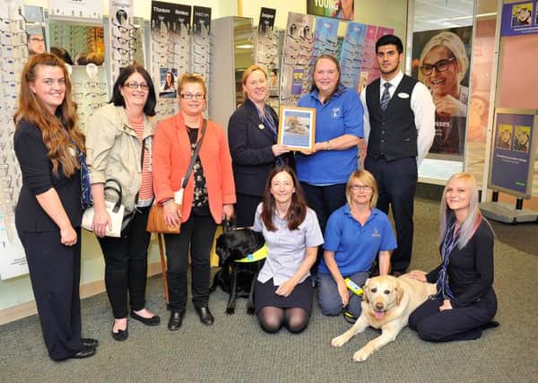 Val Cook (Guide Dogs for the Blind) presents a framed guide dog photograph to Sharon Courtney (Specsavers) with (standing left to right) Kirby Raper (Specsavers), Philippa Gretton, Julie Gafney and her guide dog Valerie and Faisal Mahmood (Specsavers) along with (front left to right) Katherine Brown (Specsavers), Sue Lendrem with guide dog Bliss and Carrie Dawes (Specsavers). Photograph by FRANK REID