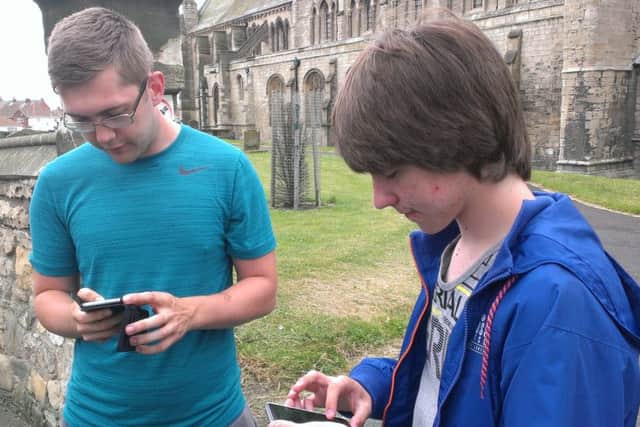 Matthew Libbey and Reiss Luke playing Pokemon Go around St Hilda's Church on the Headland