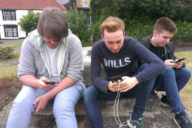 From left, Tony Reed, Ethan Scott and Michael Stalley playing Pokemon Go around St Hilda's Church on the Headland